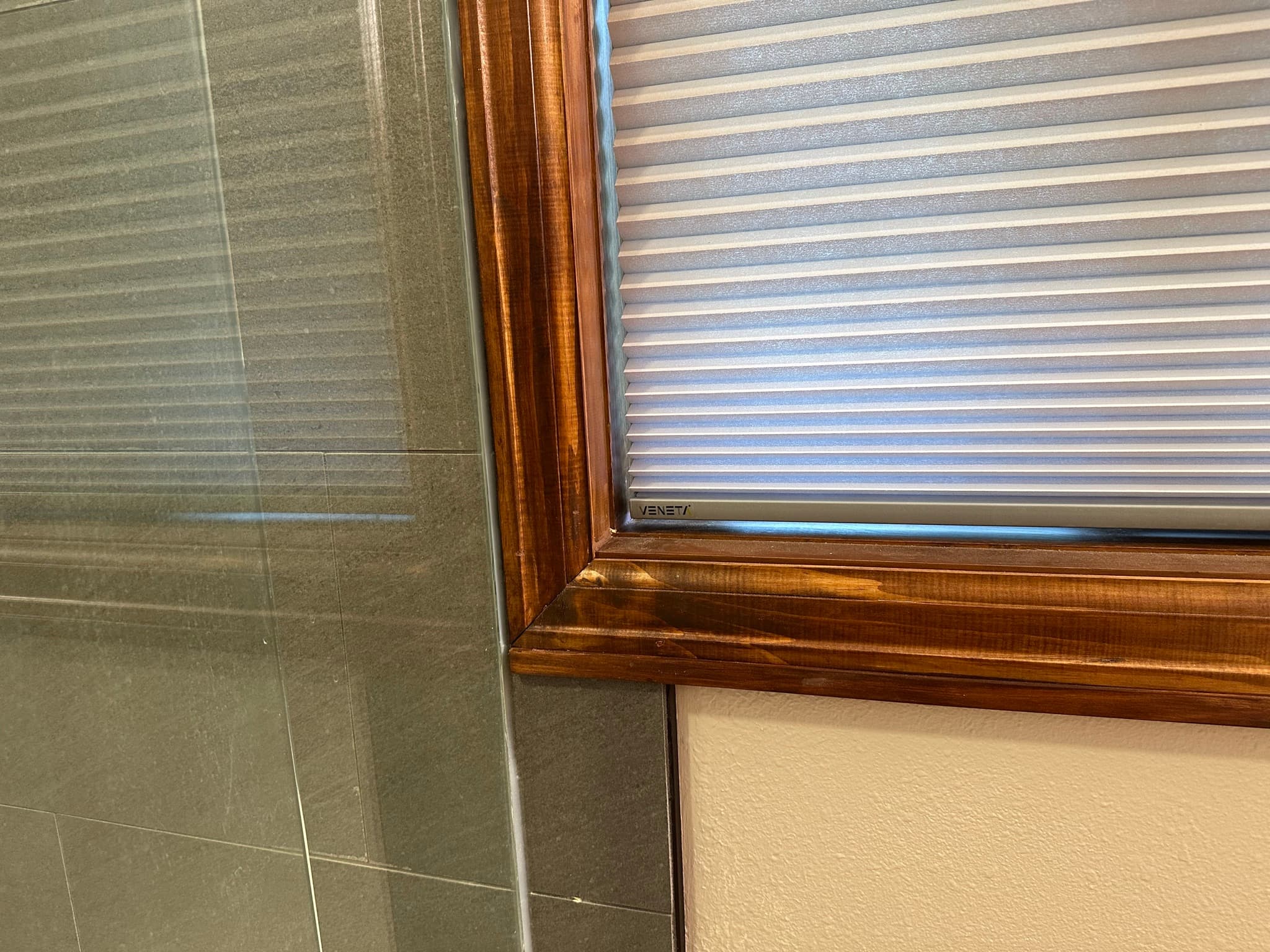 Close-up of the new window casing: torched-wood (shou sugi ban) finish with grain raised and darkened, joining the textured wall.