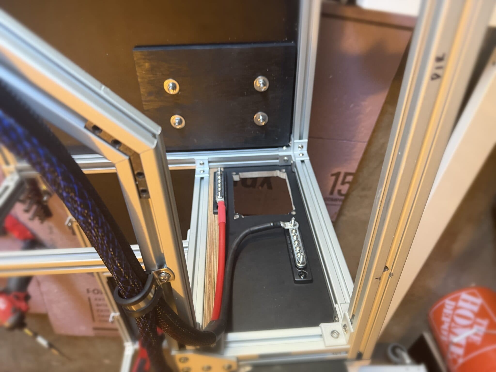 Inside a module frame: a tin-plated copper busbar mounted through a cutout in the black panel with a heavy black cable landed on one end.
